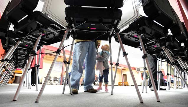 Child watches father vote (Photo: Erik Lesser / The New York Times)